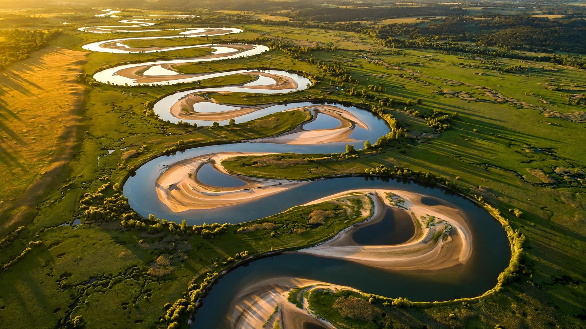 Aerial view of S-shaped river meanders and oxbow lakes at golden hour